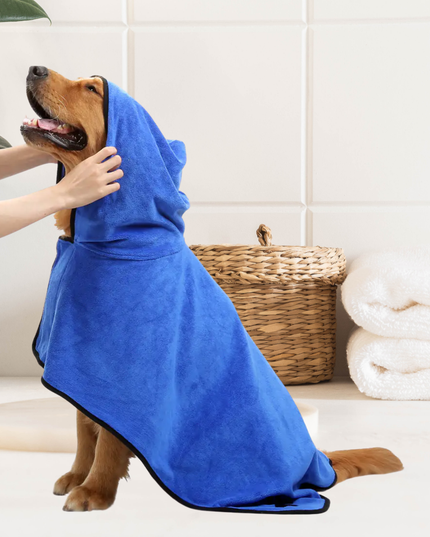 Dog wearing a blue towel with a person assisting, in a bathroom setting.