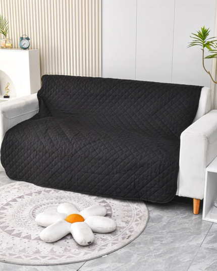 Black sofa cover on a white sofa in a living room setting with decor elements.