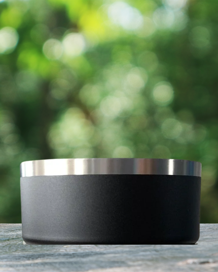Black and silver cylindrical container on a wooden surface with a blurred green background