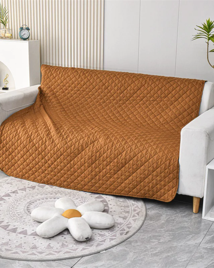 Brown quilted sofa cover on a white sofa in a living room setting.