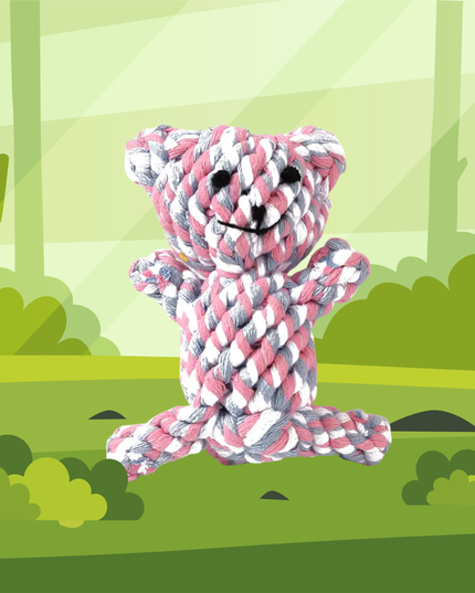 Pink and white rope teddy bear toy in a forest setting