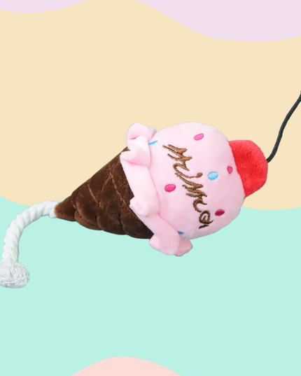 Plush toy shaped like a ice cream cone with a cat on top against a colorful background