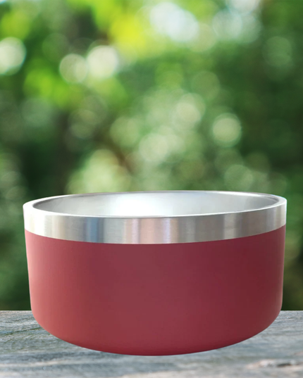 Red and silver bowl on a wooden surface with a blurred green background