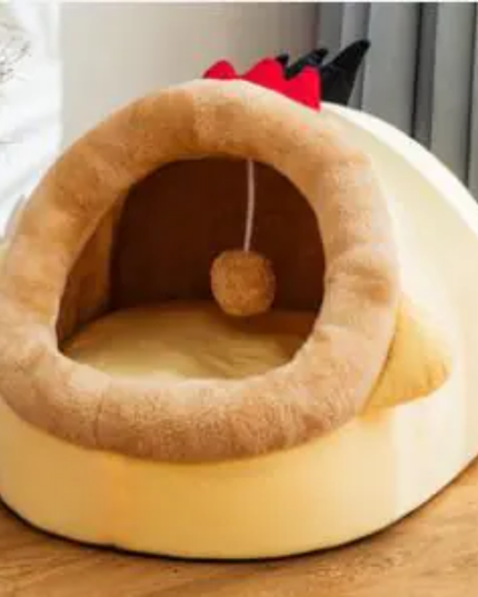 Pet bed designed like a small house with a ball inside on a wooden surface.