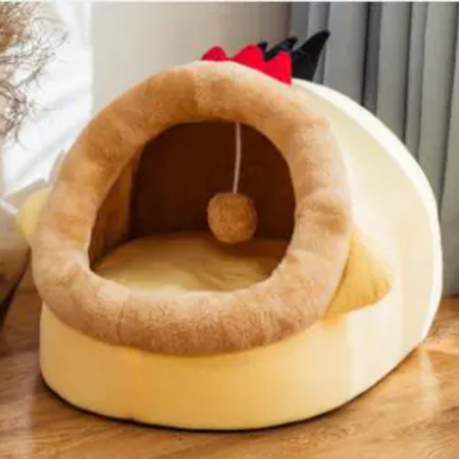 Pet bed designed like a small house with a ball inside on a wooden surface.
