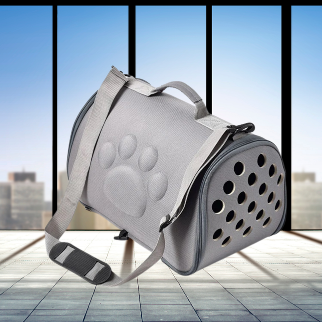 Gray pet carrier with paw print design on a light wooden floor.