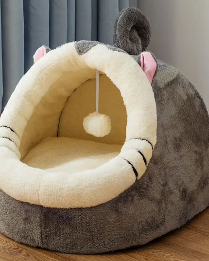 Cat-shaped pet bed with a soft interior on a wooden floor.