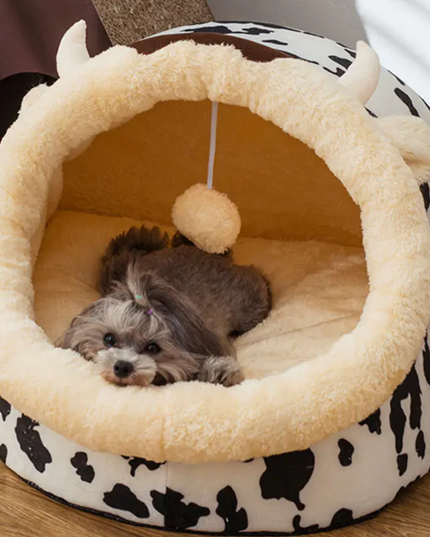 Dog lying in a round pet bed with a cow print base
