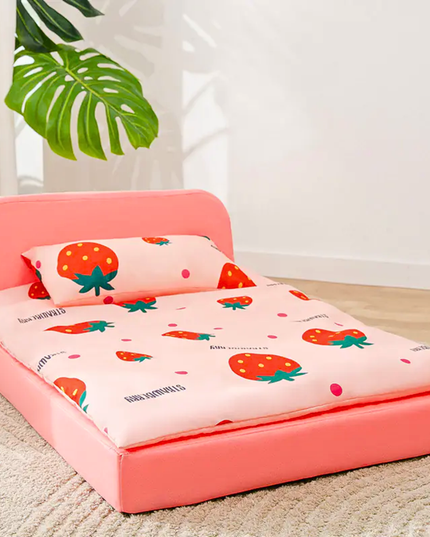Pink children's bed with strawberry patterned bedding and pillow on a carpeted floor.