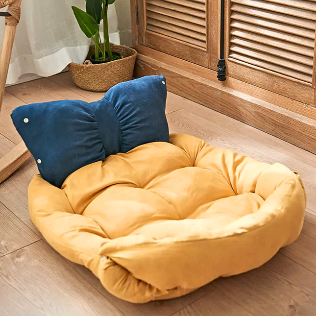 Yellow pet bed with a blue pillow on a wooden floor