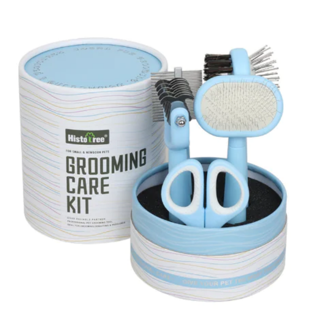 Pet grooming care kit with scissors, brush, and other tools in a cylindrical container on a white background.