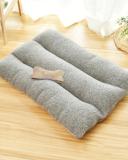 Gray pet bed on a wooden floor with a small pillow on top