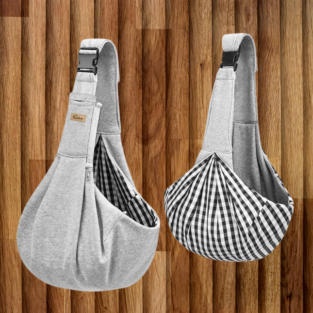 Two gray pet sling bags with checkered lining on a wooden background