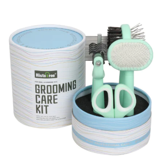 Grooming care kit with scissors, brush, and comb in a cylindrical container on a white background.