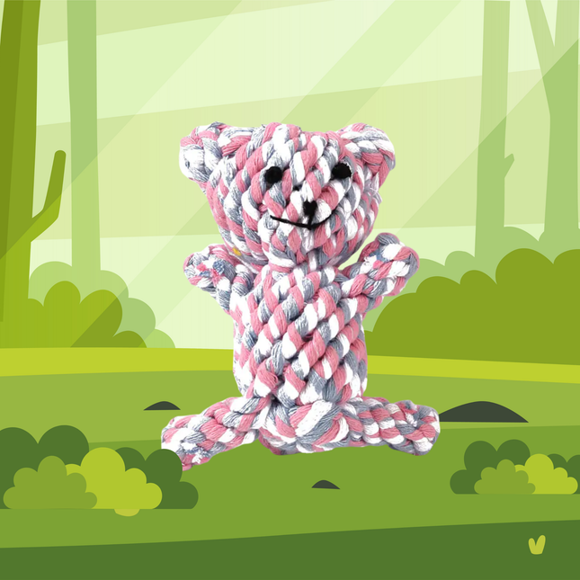 Pink and white rope teddy bear toy in a forest setting