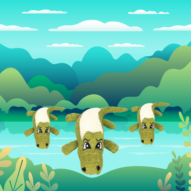 Three green and white toy goats in a forest setting with trees and water in the background.