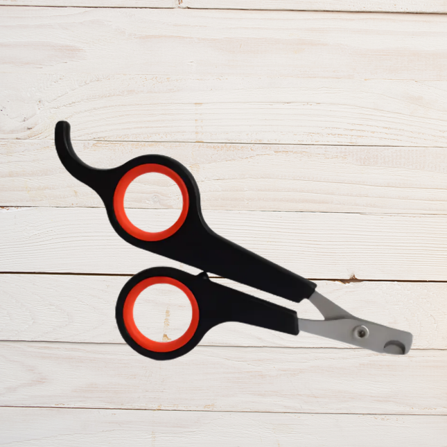 Black and red pet nail clippers on a light wooden surface