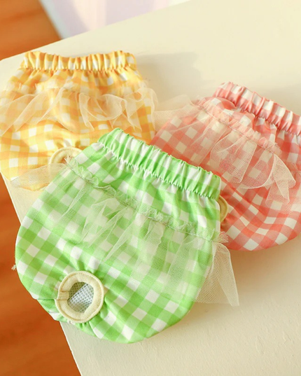 Three colorful checkered baby bloomers on a light surface.