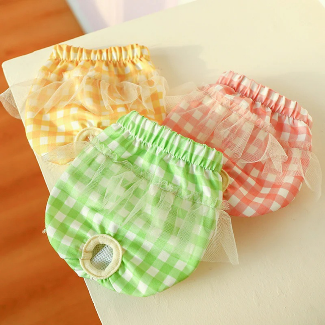 Three colorful checkered baby bloomers on a light surface.
